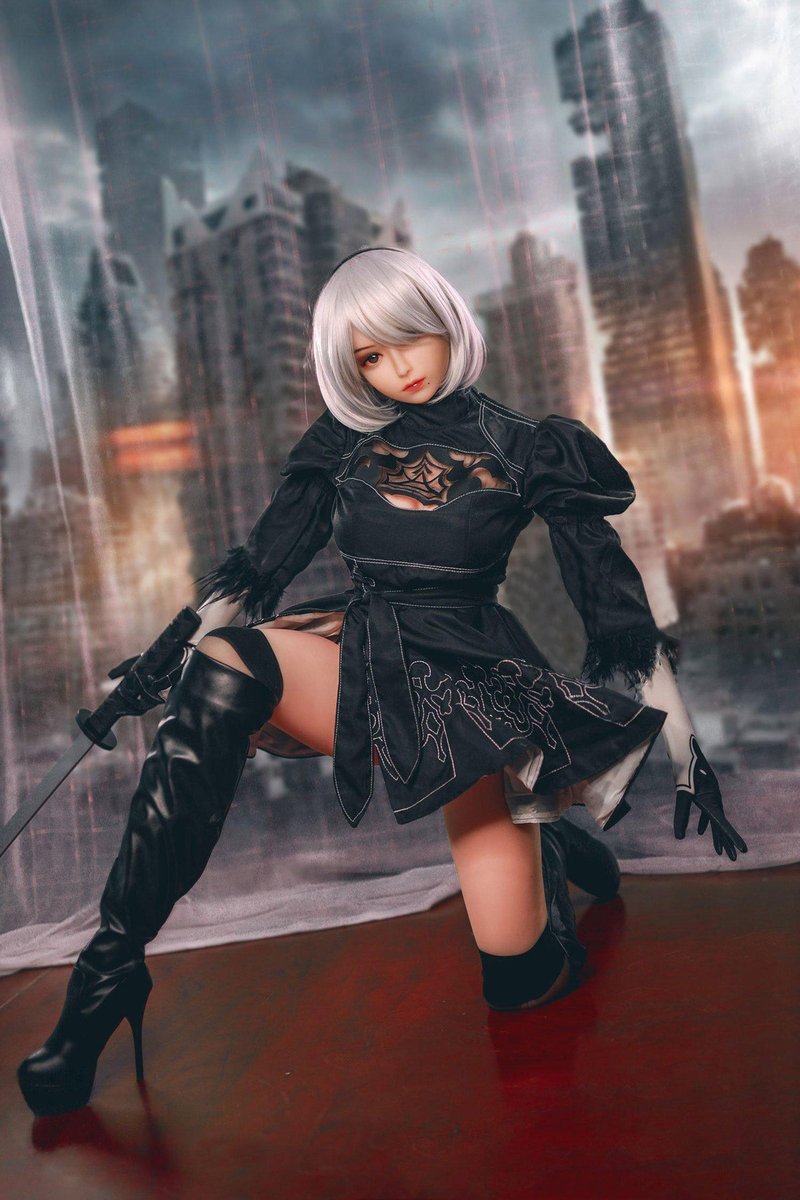 2B gaming sex doll kneeling in costume on the ruined city stage set
