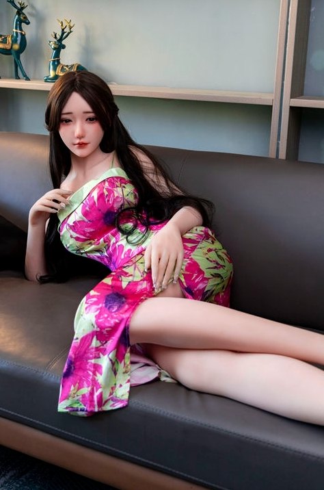 Aadhira Japanese sex doll seated, dress slit open over her thigh