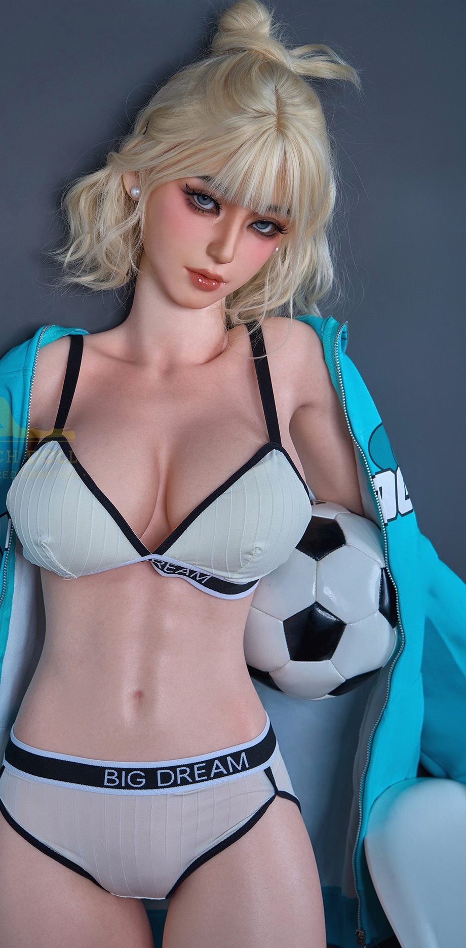 Akari, a 161 cm fitness silicone doll holding a football against a grey wall