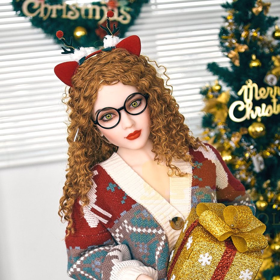 Daisy, a 150 cm doll seated by a Christmas tree with a gold gift box