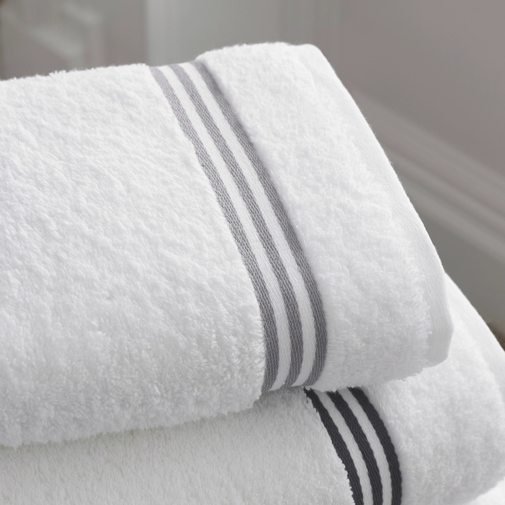 A stack of folded white bath towels with grey stripes