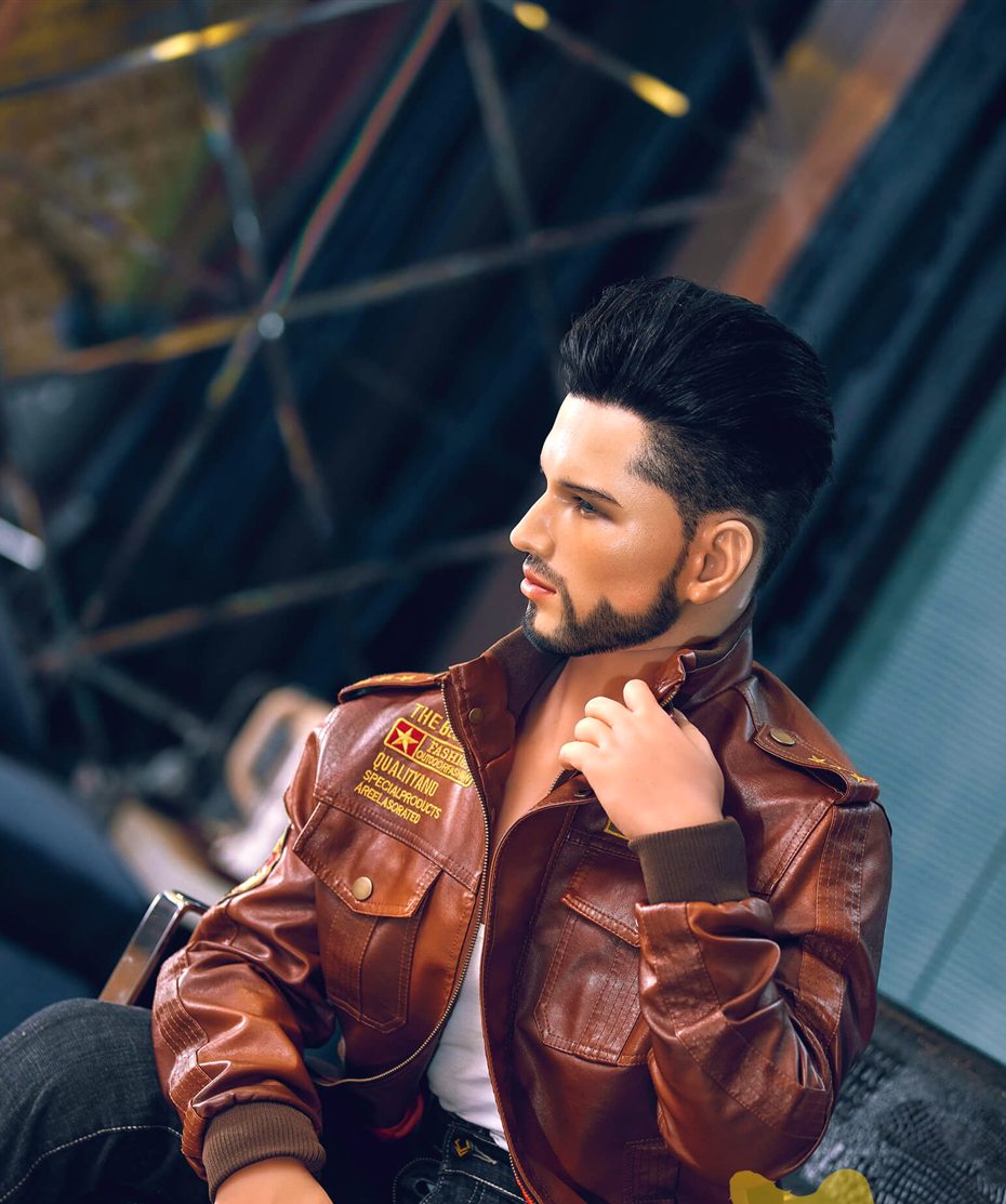 Liam, a 162 cm male sex doll seated in profile adjusting his jacket collar