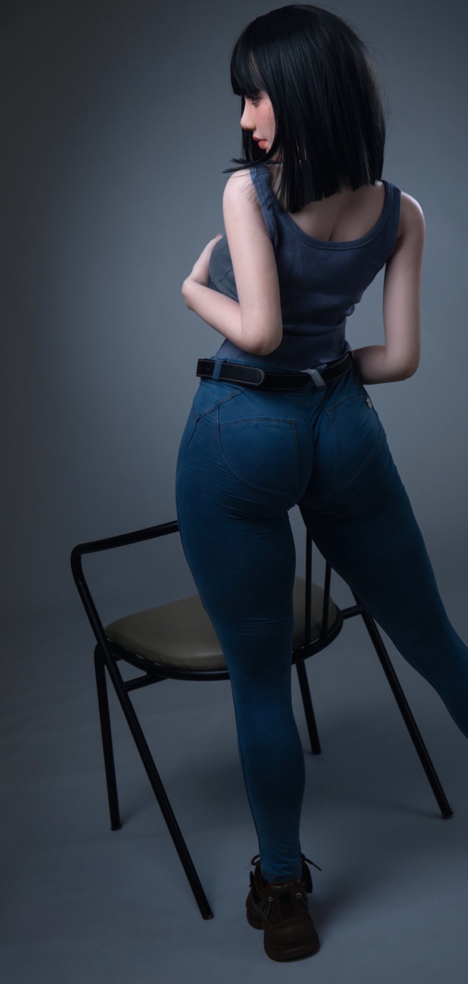 Back view of Magnolia, a 153 cm silicone doll in jeans beside a chair
