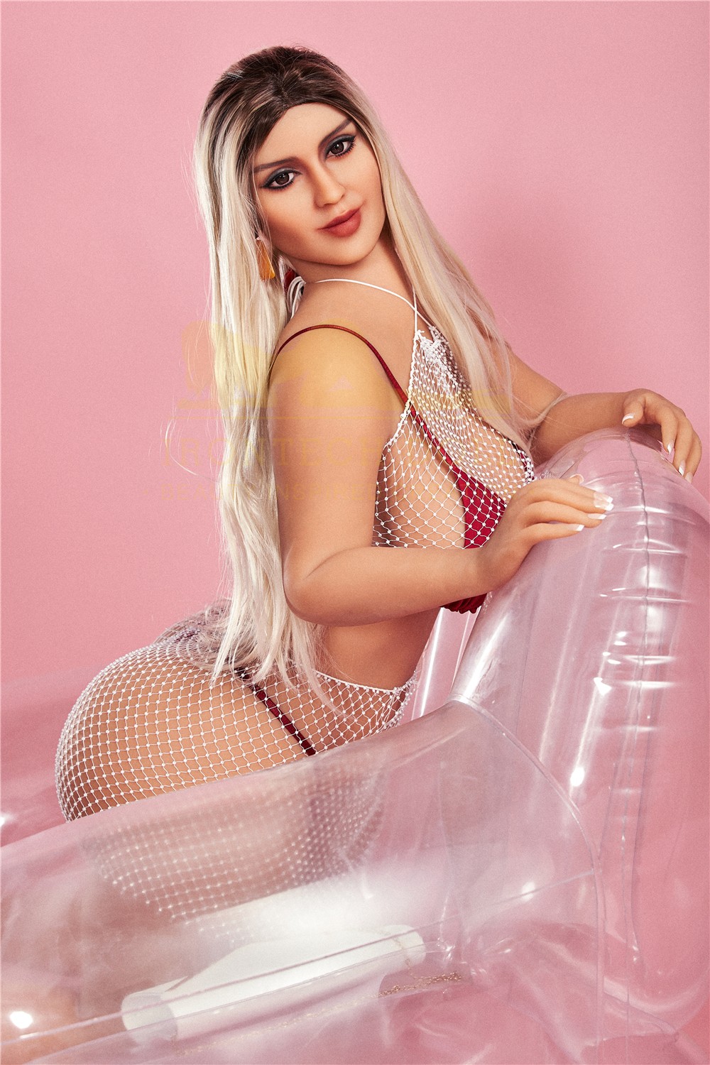 Selah, a 156 cm pawg TPE sex doll, blonde, seated on a clear chair