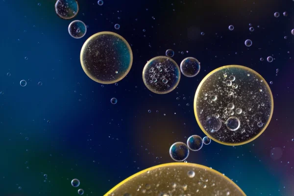 Macro of golden oil droplets suspended in dark liquid