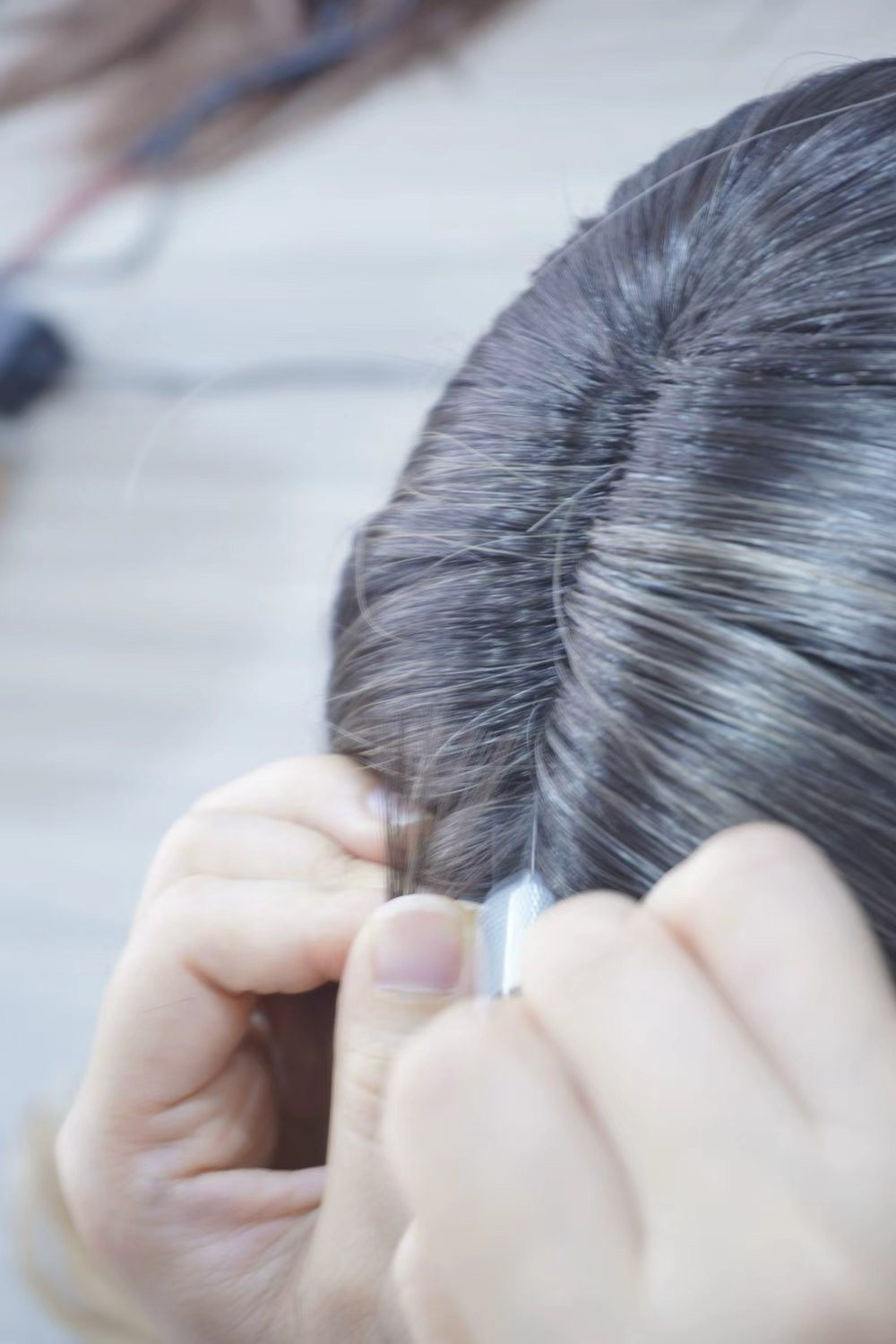 Hands knotting hair strand by strand into a sex doll wig
